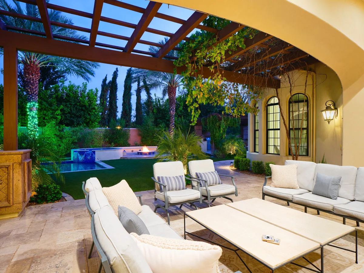 A tranquil outdoor space featuring a modern swimming pool, an inviting seating area, lush greenery, and decorative night lighting. The setting is perfect for sunset relaxation, poolside gatherings, or festive evenings outdoors.