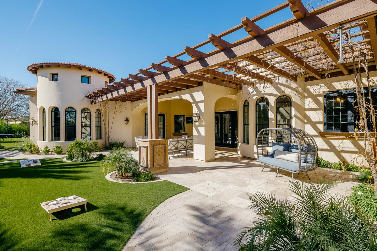 This exterior image showcases the curved architecture of the home, a welcoming pergola structure, a hanging chair, and a manicured lawn. The scene is tranquil and inviting, presenting the perfect secure, spacious backyard for pets and families to enjoy outdoor time together.