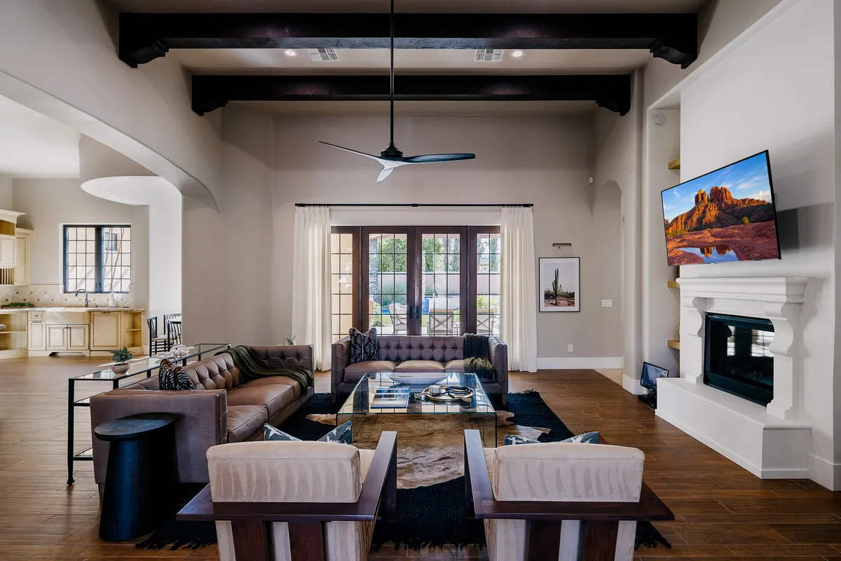 A welcoming living area with a comfortable sofa set arranged around a modern coffee table facing a prominent fireplace. Large windows flood the space with natural light, creating an inviting atmosphere ideal for social gatherings or quiet moments of relaxation.