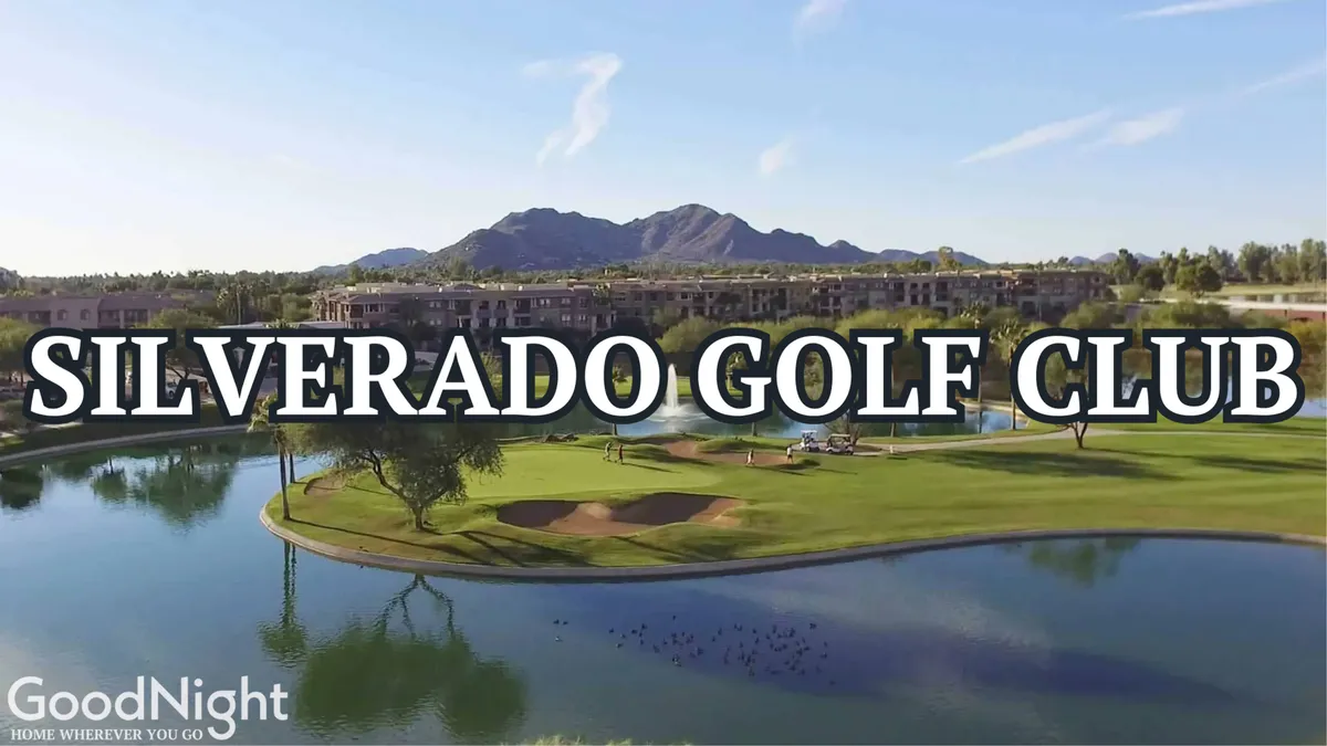 A sweeping view of a lush golf course with a serene lake, rolling greens, luxury resort buildings, and mountains creating a picturesque backdrop. The atmosphere is picturesque and relaxed, perfect for socializing or golfing.